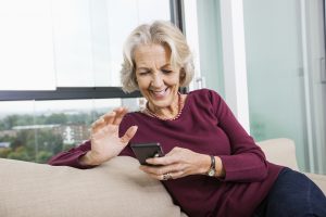 senior woman using mart phone on sofa
