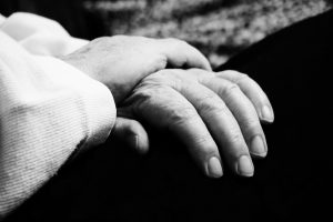 close-up of elderly person's hands folded in black and white