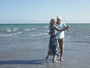 photo of senior couple dancing on the beach