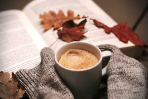 cozy photo of hot drink, book, and fall leaves