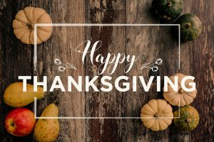 rustic "happy thanksgiving" graphic with gourds and squashes in the background